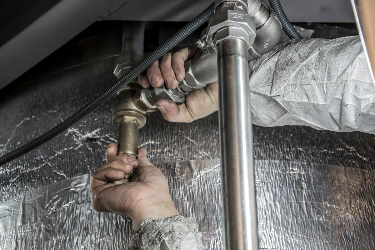 Plumber working on brass pipe fittings under a sink